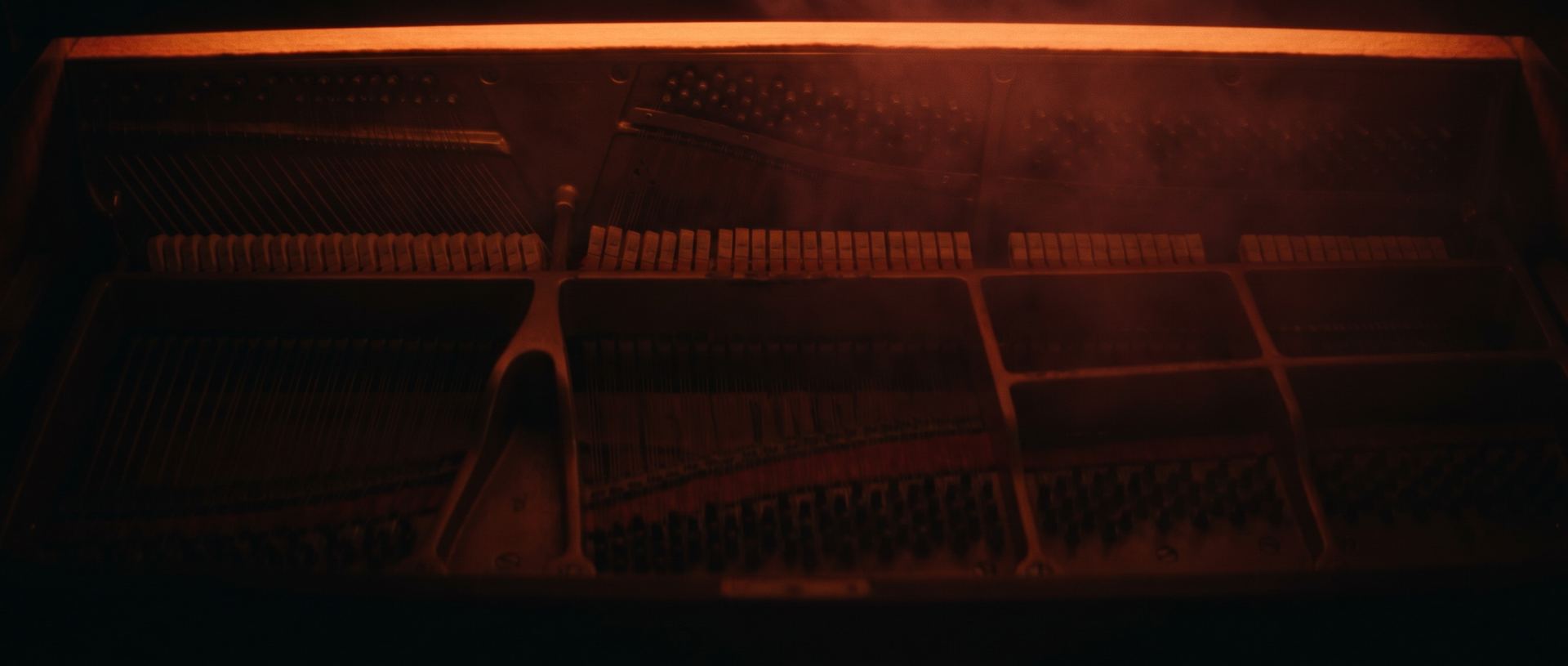 the interior of an upright piano in deep shadow